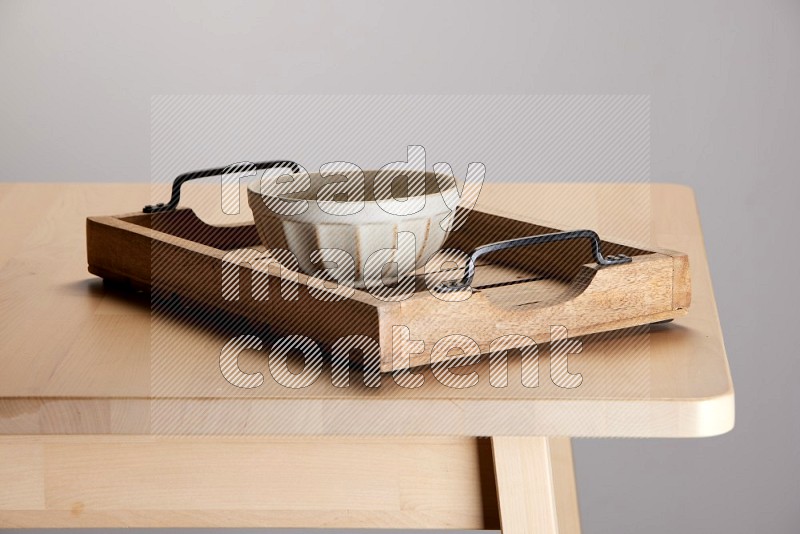 off white bowl on a light colored rectangular wooden tray with handles