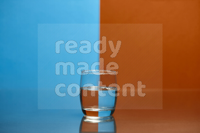 The image features a clear glassware filled with water, set against blue and dark orange background