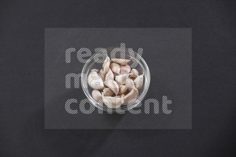A glass bowl full of garlic cloves on a black flooring