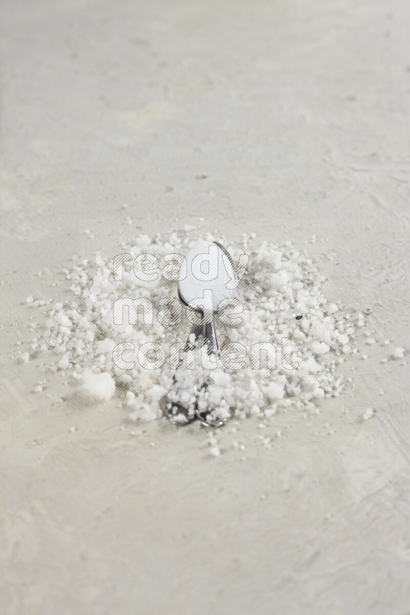 ملعقتان معدنيتان ممتلئتان بملح الطعام الناعم وملح الهايمالايا الناعم على خلفية بيضاء