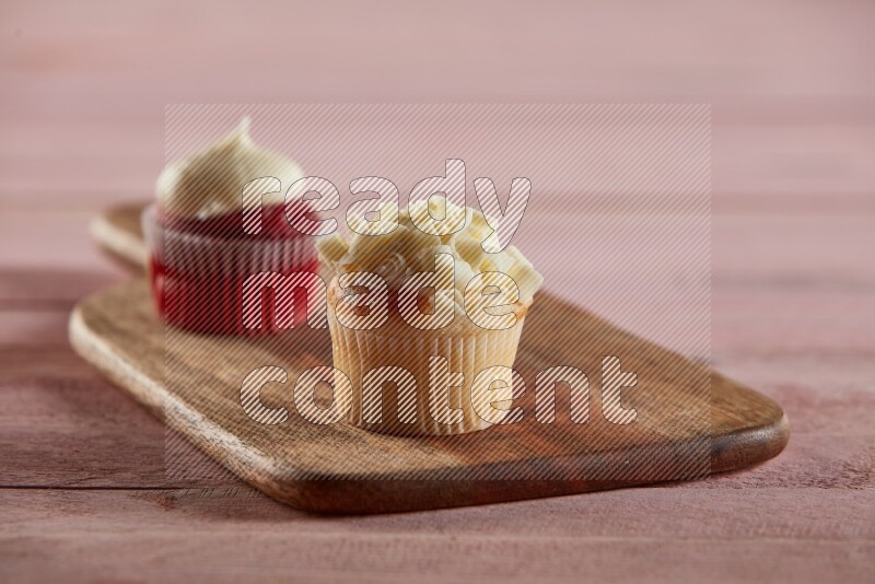 Vanilla mini cupcake topped with white chocolate curls on a wooden board