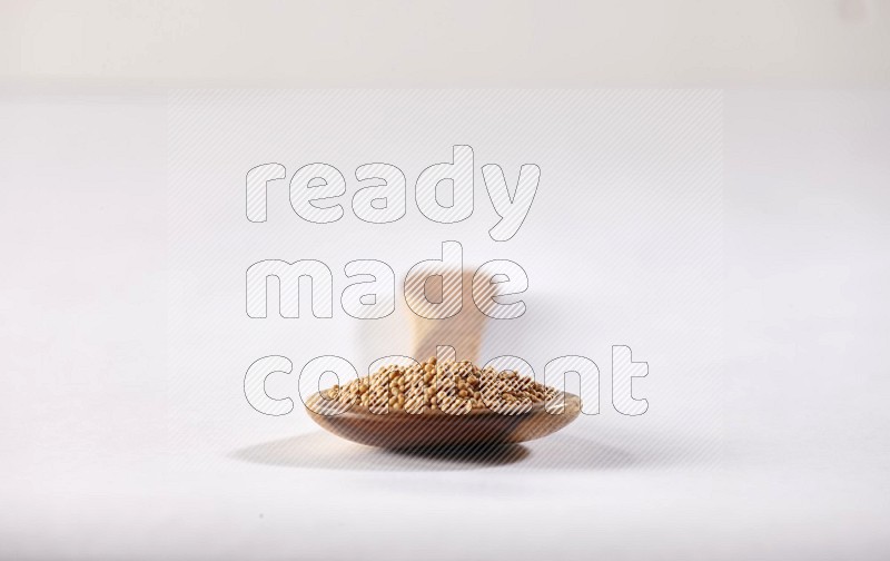 A wooden ladle full of mustard seeds on a white flooring in different angles