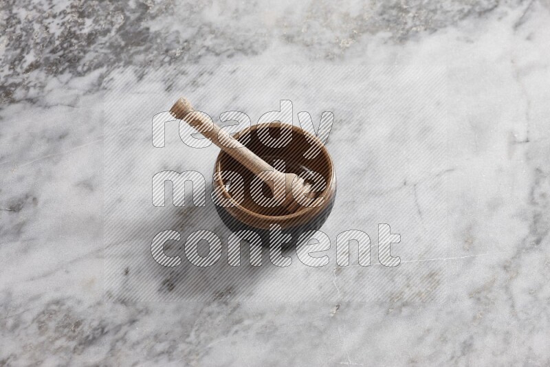 Multicolored pottery bowl with wooden honey dipper in it on grey marble background