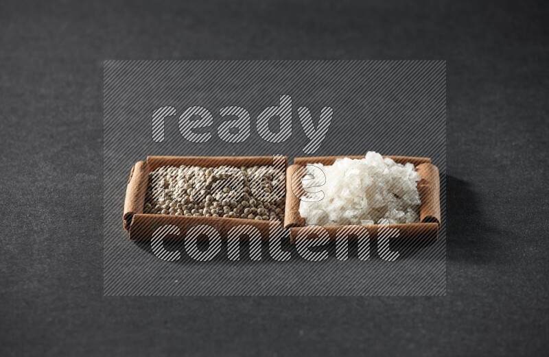 2 squares of cinnamon sticks full of white pepper and salt on black flooring