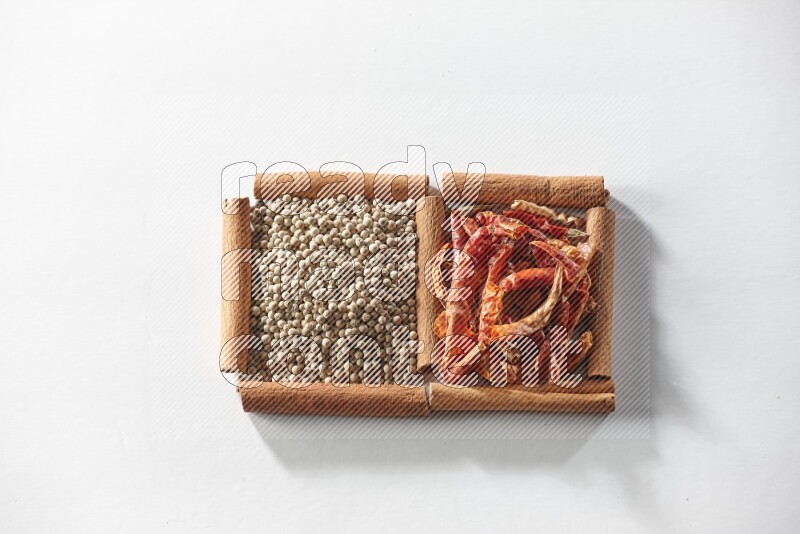 2 squares of cinnamon sticks full of red dried chilis and white pepper on white flooring