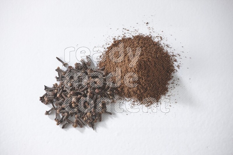 2 piles of cloves grains and cloves powder on a white flooring
