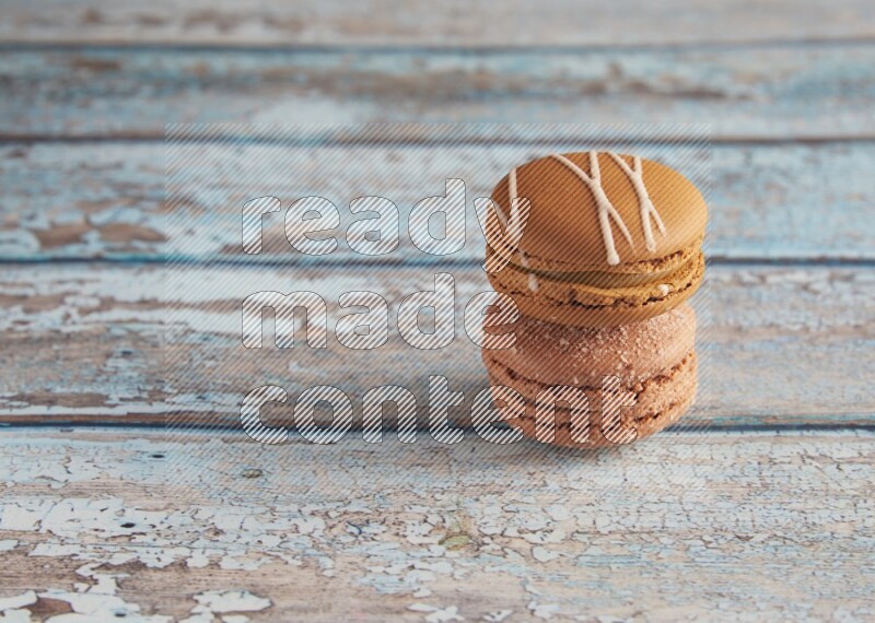 45º Shot of of two assorted Brown Irish Cream, and Brown Hazelnuts macarons  on light blue background