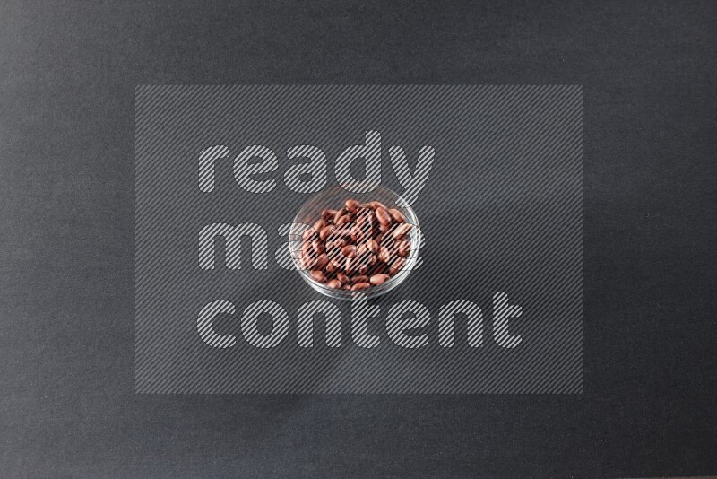 وعاء زجاجي ممتلئ بالفول السوداني على خلفية سوداء