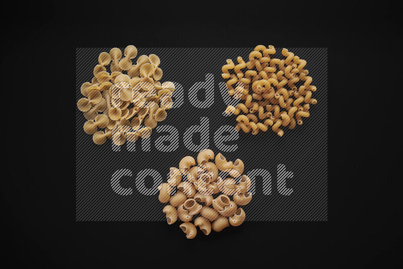 Different pasta types in bunches on black background