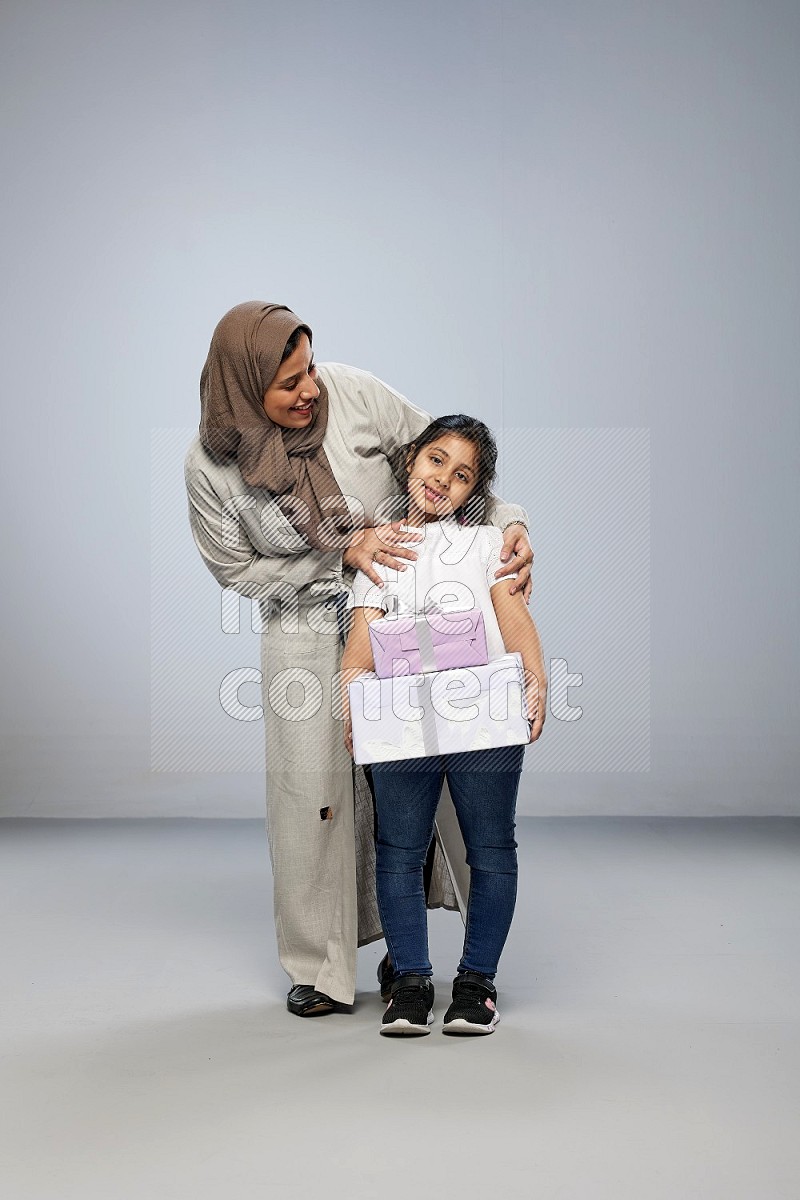 A girl giving a gift to her mother on gray background