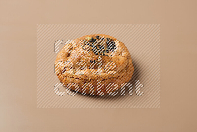 a whole Hasawi cookie with grains on a brown background