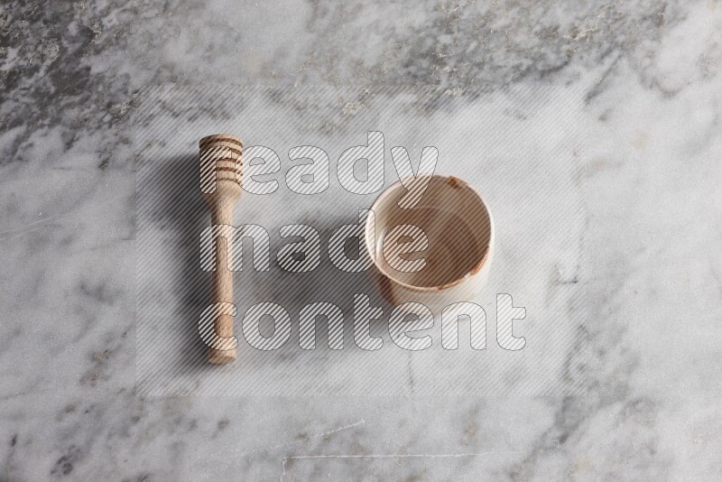 Decorative pottery bowl with wooden honey dipper on the side on grey marble background