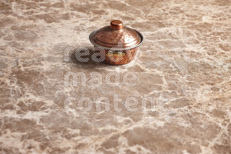 A small copper pot on beige marble background
