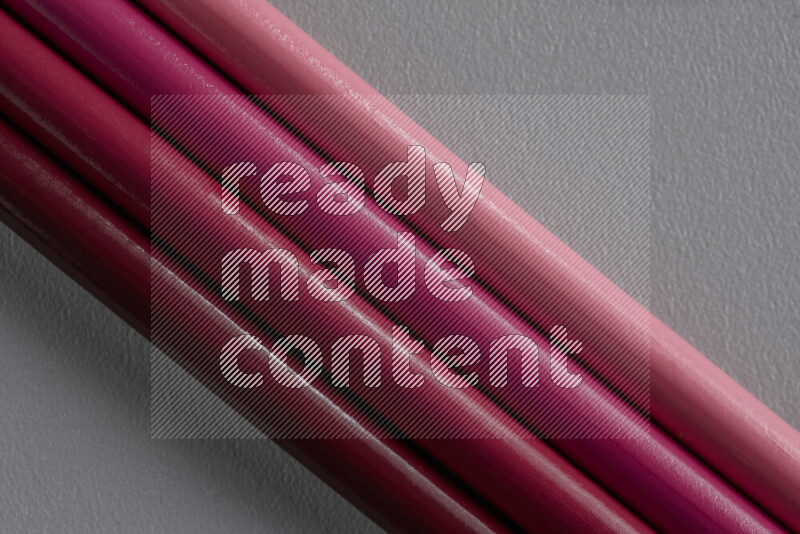 مجموعة من أقلام الرصاص الملونة مرتبة لتعرض تدرجا من الألوان الوردية علي خلفية رمادية