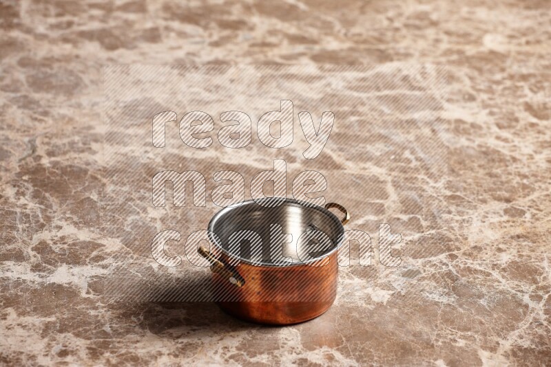 A small copper pot on beige marble background