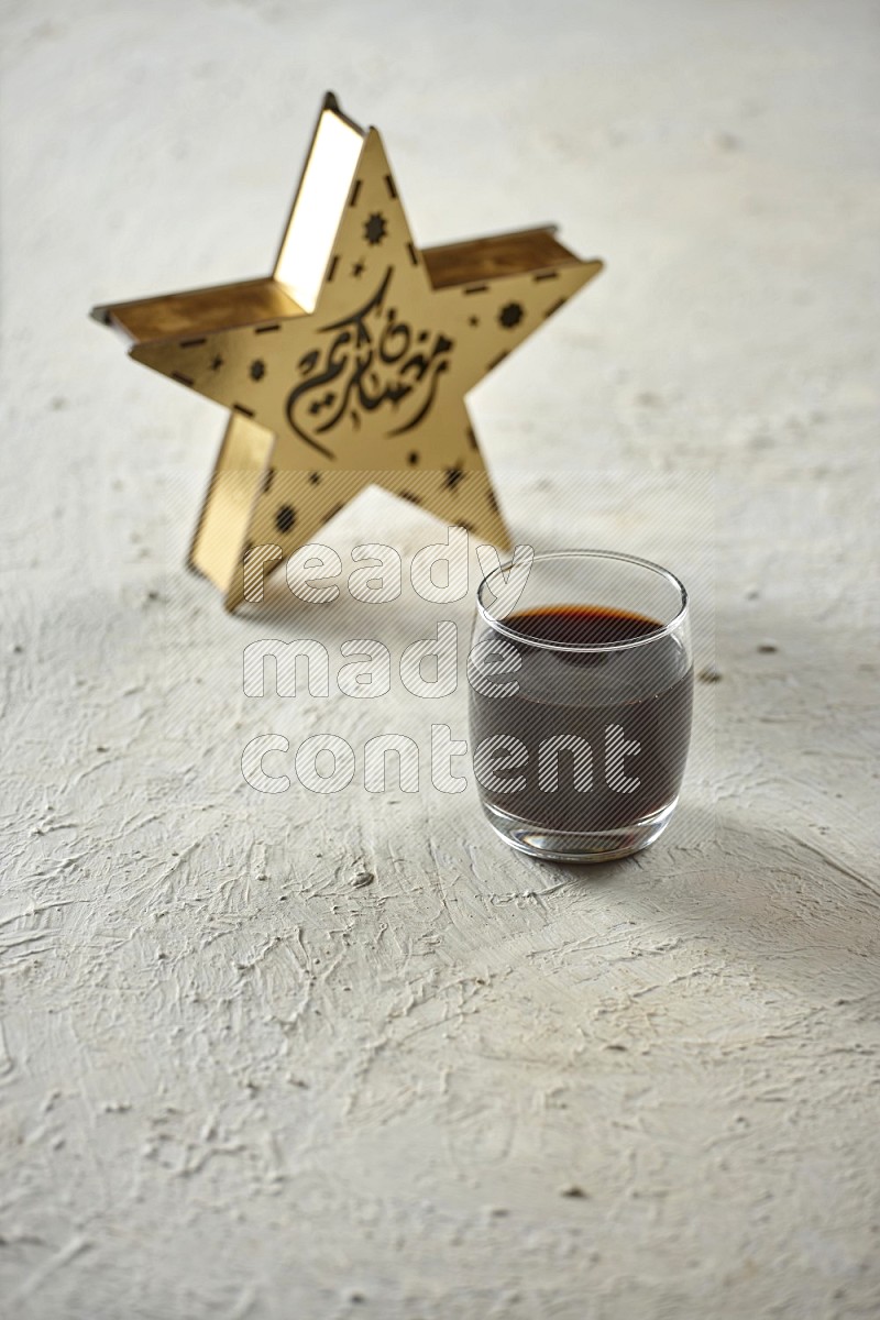 A star lantern with drinks, dates, nuts, prayer beads and quran on textured white background