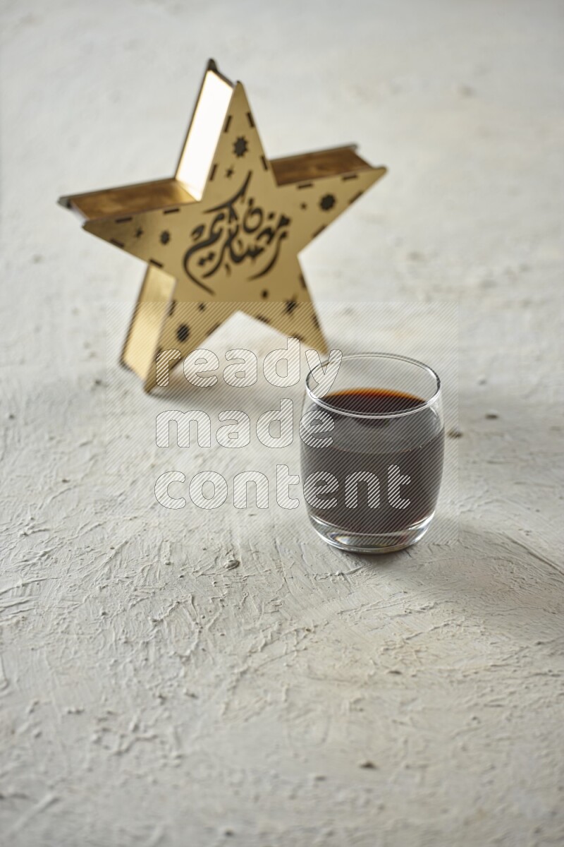 A wooden golden star lantern with different drinks, dates, nuts, prayer beads and quran on textured white background