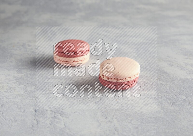 45º Shot of two Pink Litchi Raspberry macarons  on white  marble background