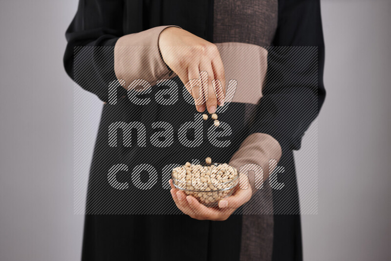 Woman in abaya holding different kinds of legumes in different positions