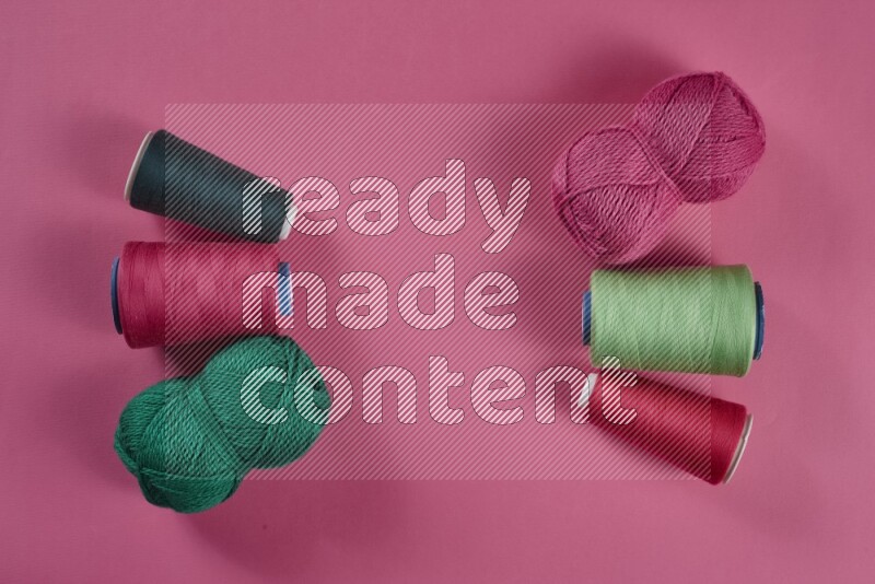 A green and pink collection of sewing and tailoring tools arranged on a pink background