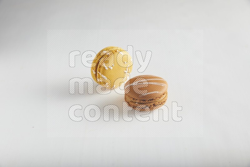 45º Shot of of two assorted Brown Irish Cream, and Yellow Piña Colada macarons on white background