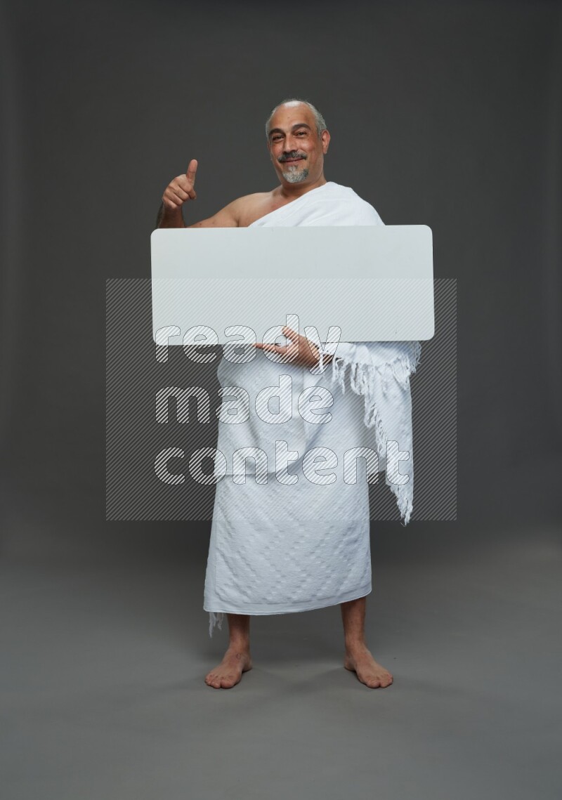 A man wearing Ehram Standing holding social media sign on gray background