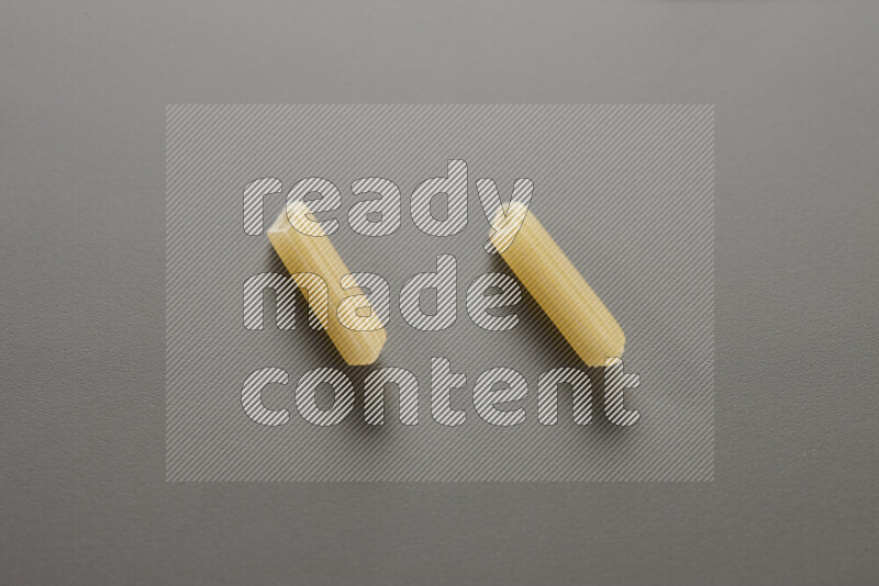 Mini penne pasta on grey background