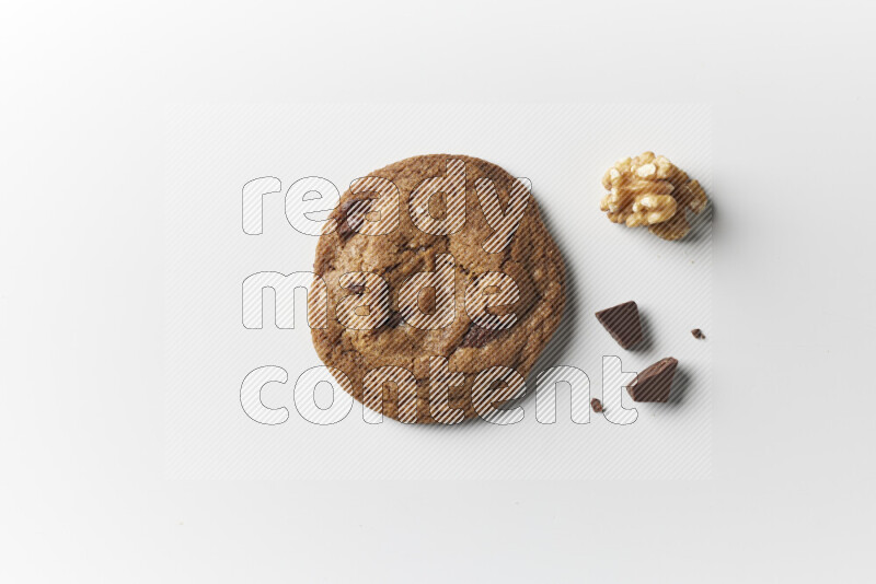 A single chocolate chips cookie with chocolate and walnuts beside it on a white background