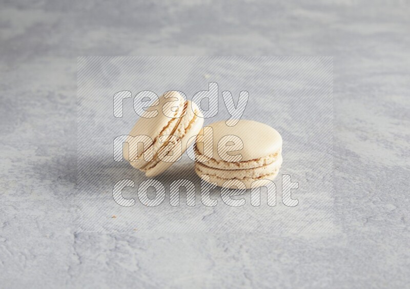45º Shot of two white marbleCaramel fleur de sel macarons  on white  marble background