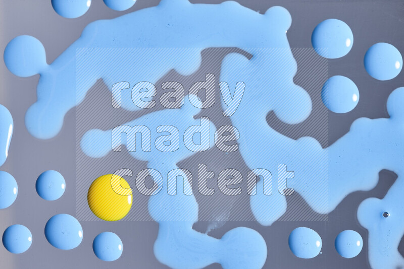 Close-ups of abstract blue and yellow paint droplets on the surface