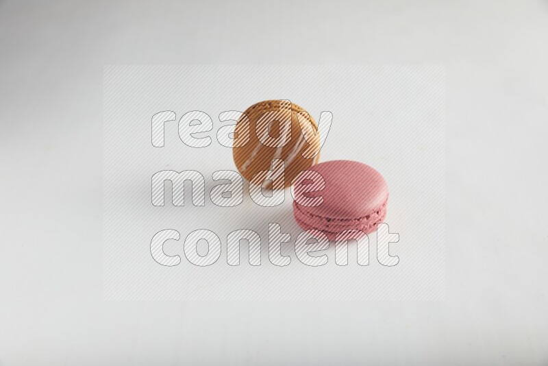 45º Shot of of two assorted Brown Irish Cream, and Pink Raspberry macarons on white background