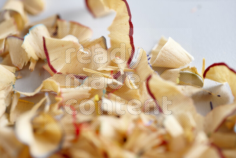 A close-up showing a small pile of pencil shavings with varied color edges on grey background