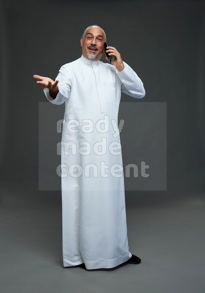 Saudi man without shomag Standing talking on phone on gray background