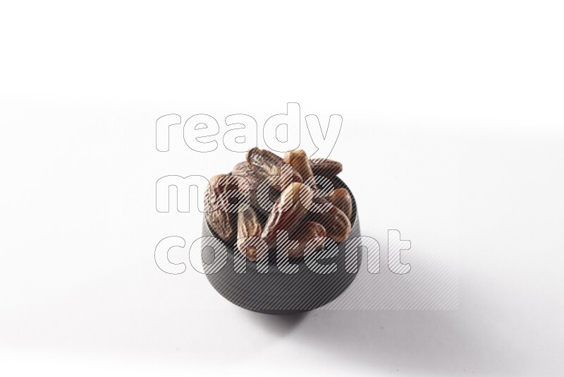 Dates in a black pottery bowl on white background