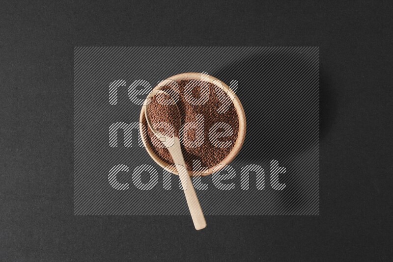 وعاء خشبي ممتلئ ببذور حب الرشاد وملعقة خشبية ممتلئة فوقه علي خلفية سوداء