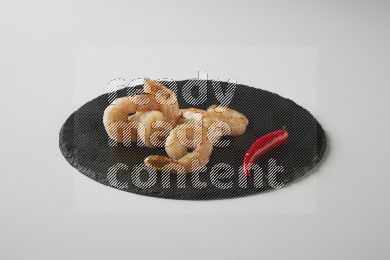five grilled shrimps  on a black slate direct  on a white back ground