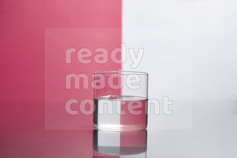 The image features a clear glassware filled with water, set against white and pink background