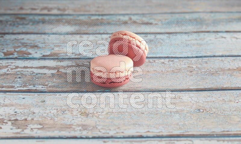 45º Shot of two Pink Litchi Raspberry macarons on light blue wooden background