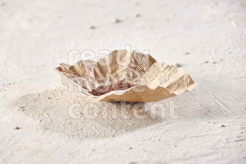 A crumpled piece of paper full of garden cress on a textured white flooring in different angles