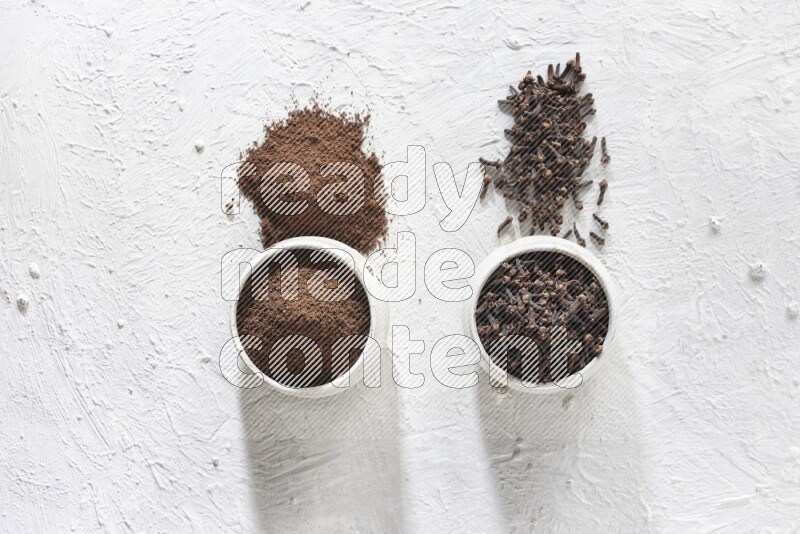 وعاءين من السيراميك بيج اللون، أحدهما مملوء بالقرنفل والآخر مملوء بالبودرة على أرضية بيضاء