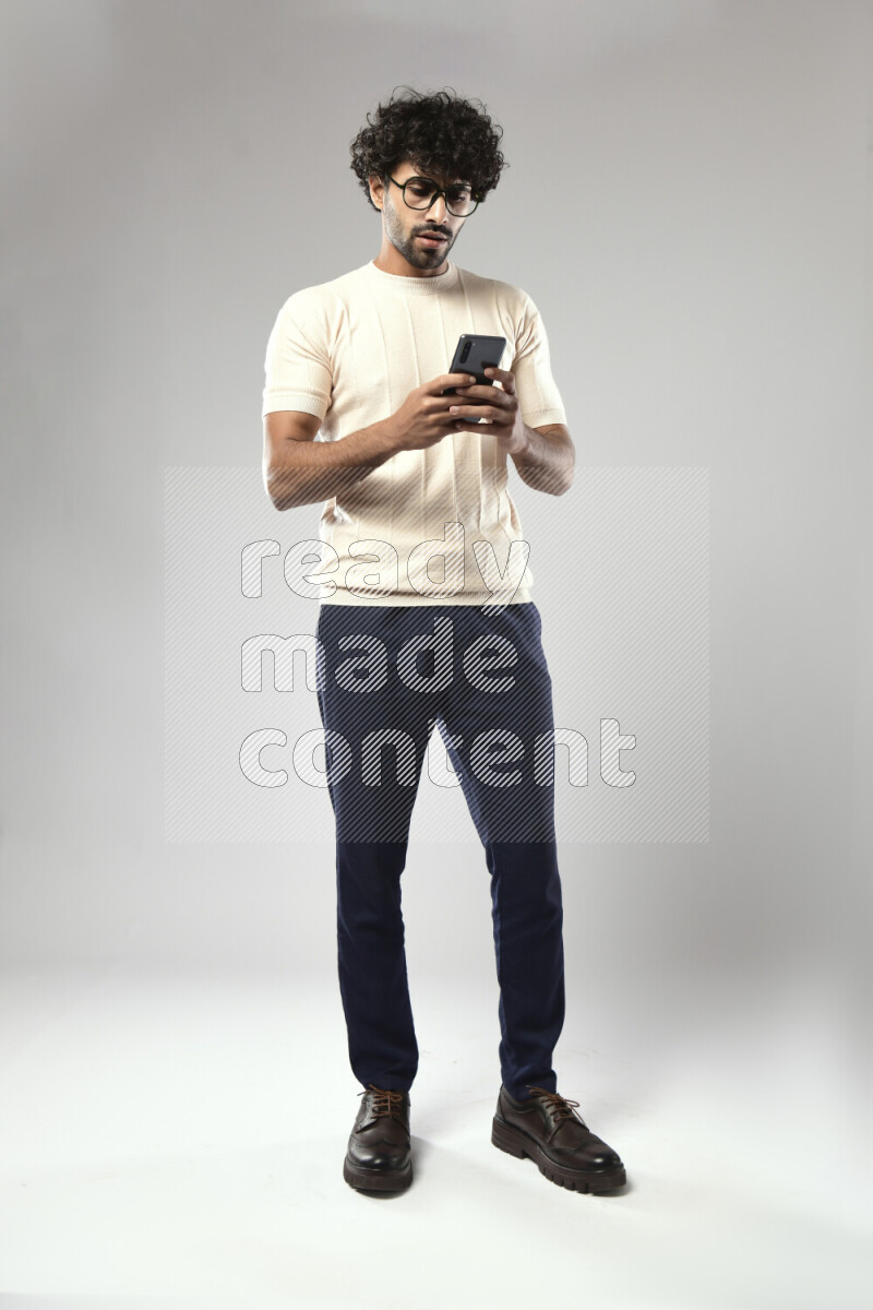 A man wearing casual standing and texting on the phone on white background