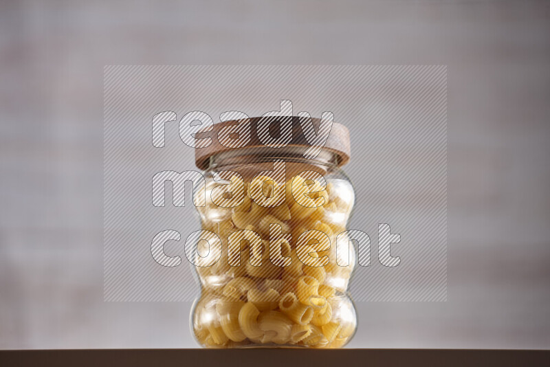 Raw pasta in glass jars on beige background