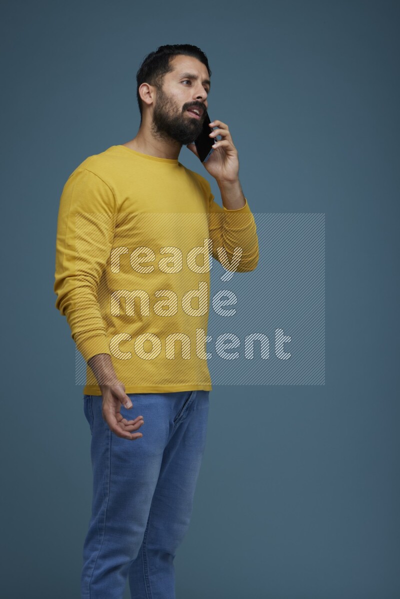 A man having a calling in a blue background wearing a yellow shirt