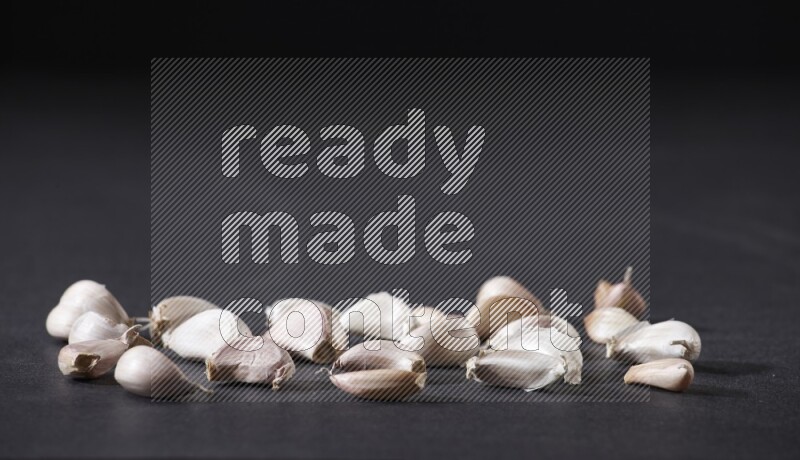 بعض فصوص الثوم متناثرة على أرضية سوداء