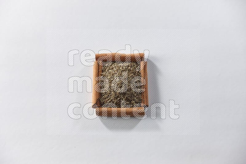 A single square of cinnamon sticks full of cumin on white flooring