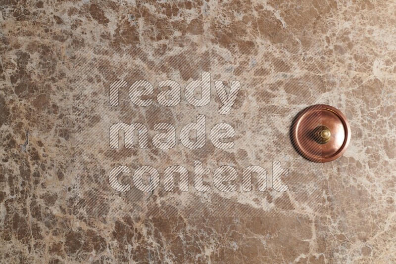 A small copper pot on beige marble background
