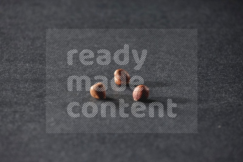 3 peeled hazelnuts on a black background in different angles