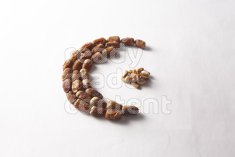 Dates in a crescent shape with nuts on white background