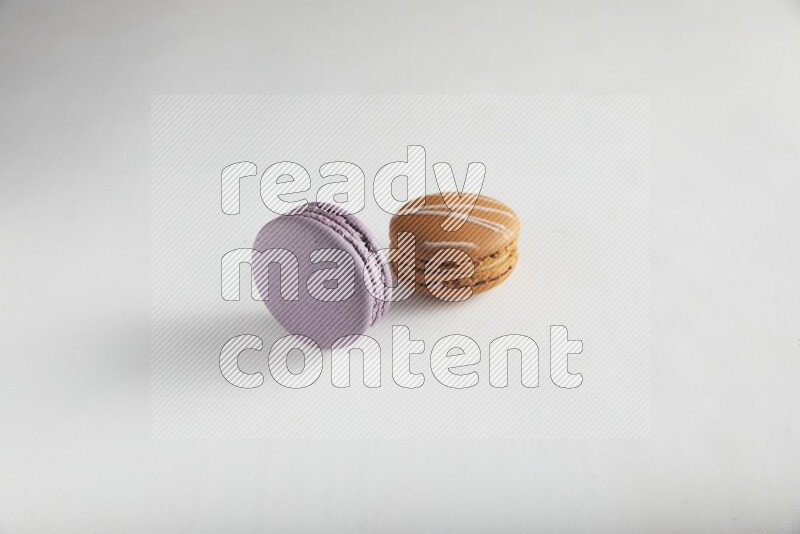45º Shot of of two assorted Brown Irish Cream, and Purple Blueberry macarons on white background