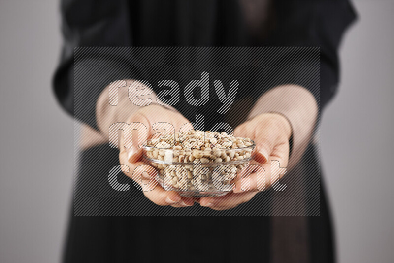 Woman in abaya holding different kinds of legumes in different positions